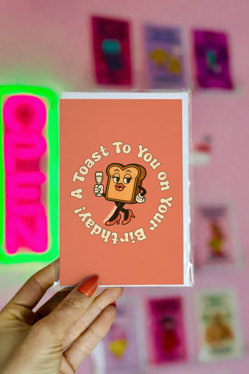 Orange birthday card featuring glamorous toast holding champagne glass with circular text “A Toast To You On Your Birthday.”
