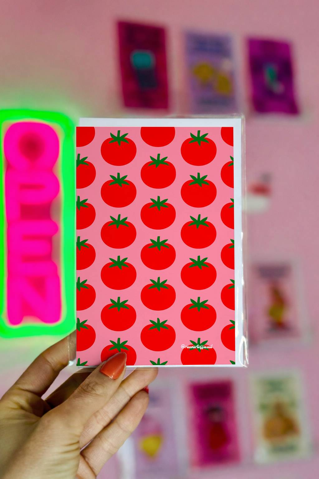 Greeting card featuring a repeating pattern of bold red tomatoes with green stems on a soft pink background in a minimalist Italian summer style.