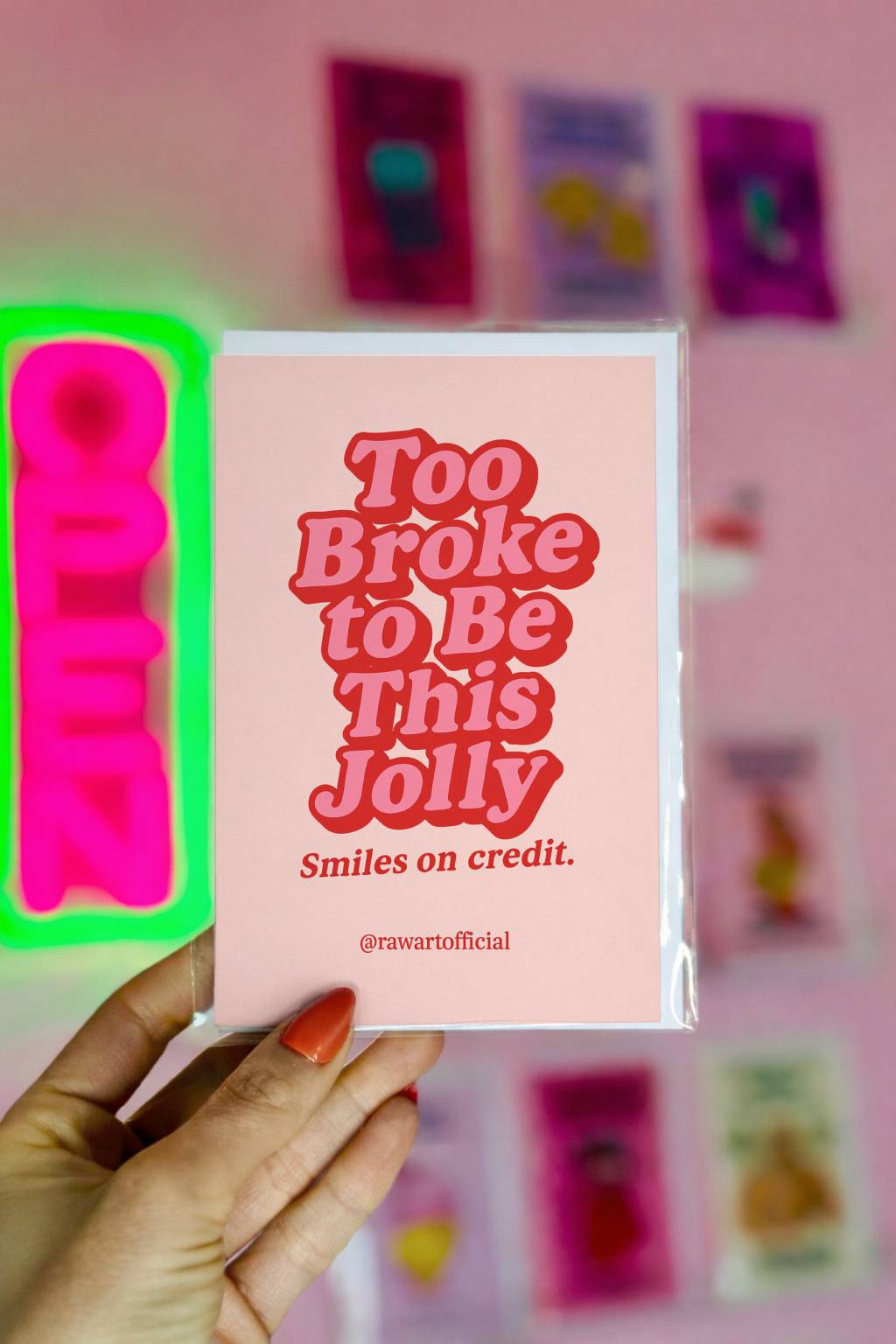Minimalist funny Christmas card with bold retro text “Too broke to be this jolly smiles on credit” on a soft pink background