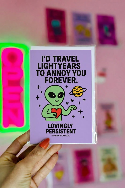 Green alien holding red heart in space with planet and hearts, text “I’d Travel Lightyears to Annoy You Forever.”