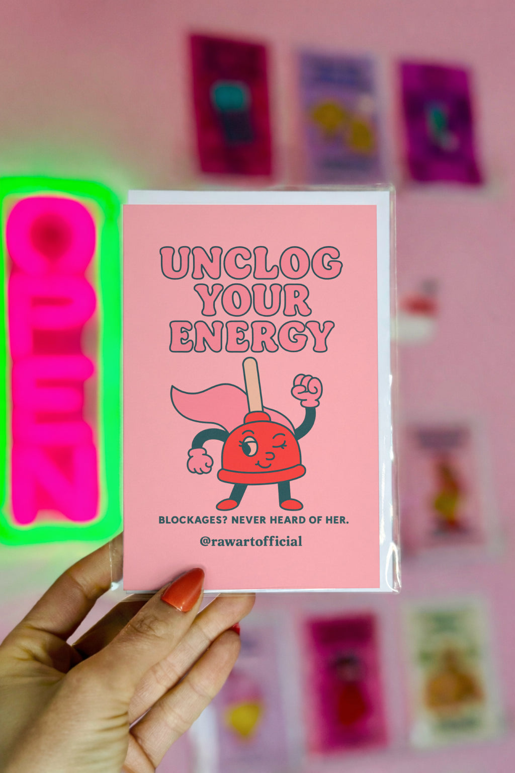 Peach encouragement card featuring cartoon plunger superhero with text “Unclog Your Energy.”