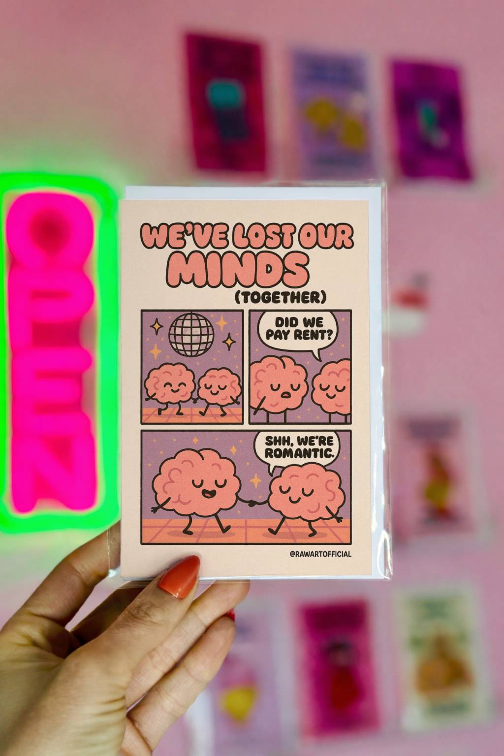 Cream greeting card with cartoon brain couple dancing under disco ball and text We’ve Lost Our Minds Together with @rawartofficial signature.