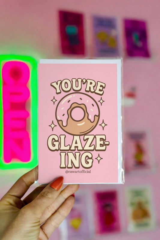 Pink congratulations card featuring a frosted donut with sparkles and the phrase “You’re Glazing.”