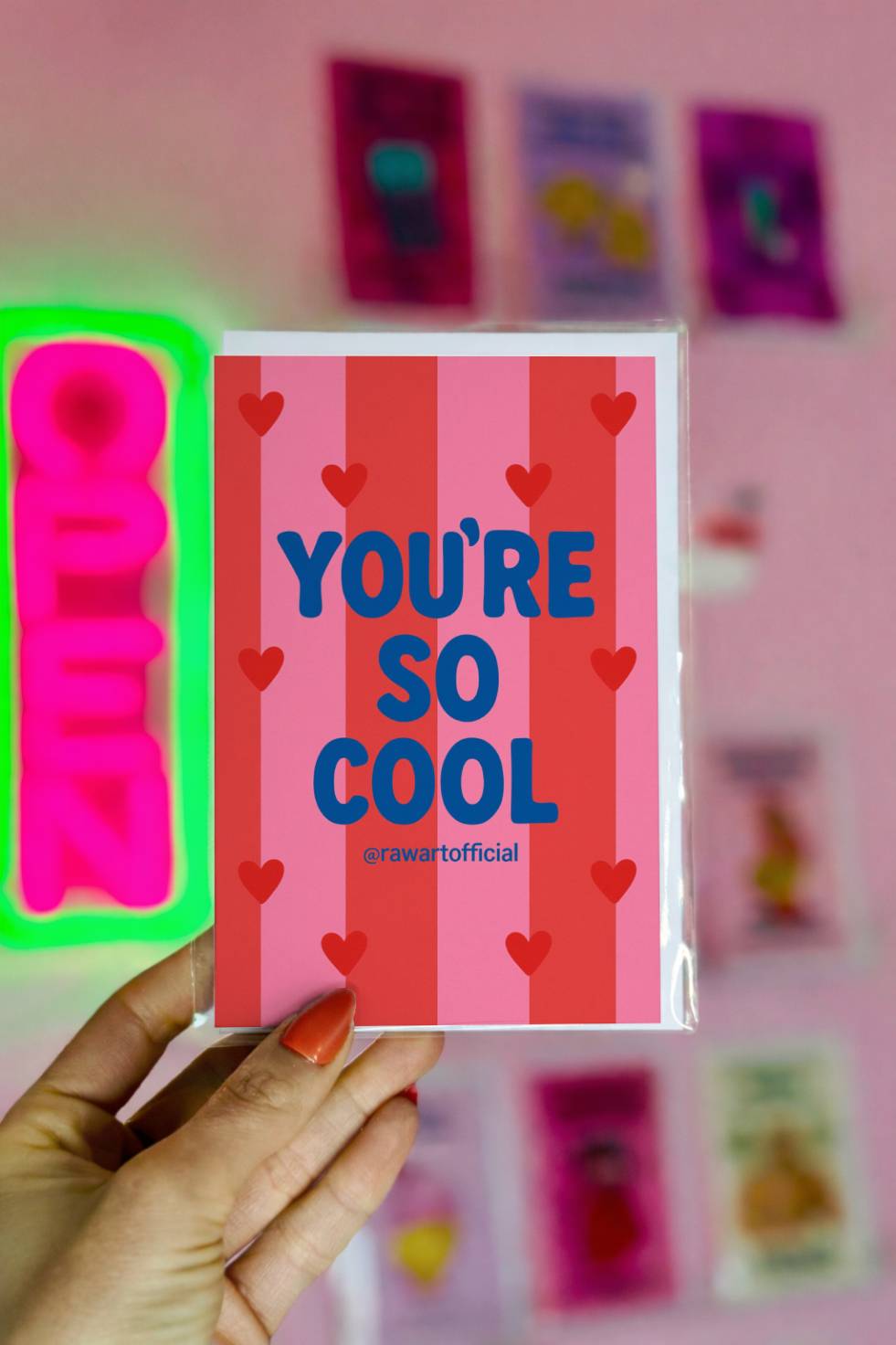 Greeting card with blue text reading “You’re So Cool” on a pink striped background with small red hearts.